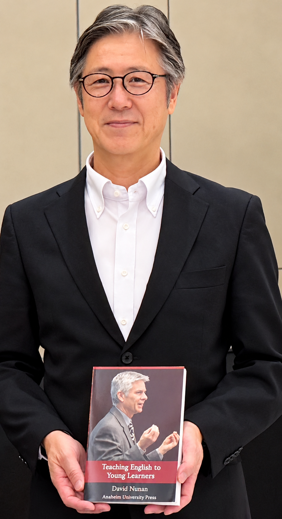 Wako City Department of Education Superintendent Tsuyoshi Ishikawa, with the Anaheim University Press textbook Teaching English to Young Learners by Dr. David Nunan